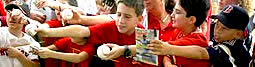 wide shot, group of kids holding out tokens to be autographed